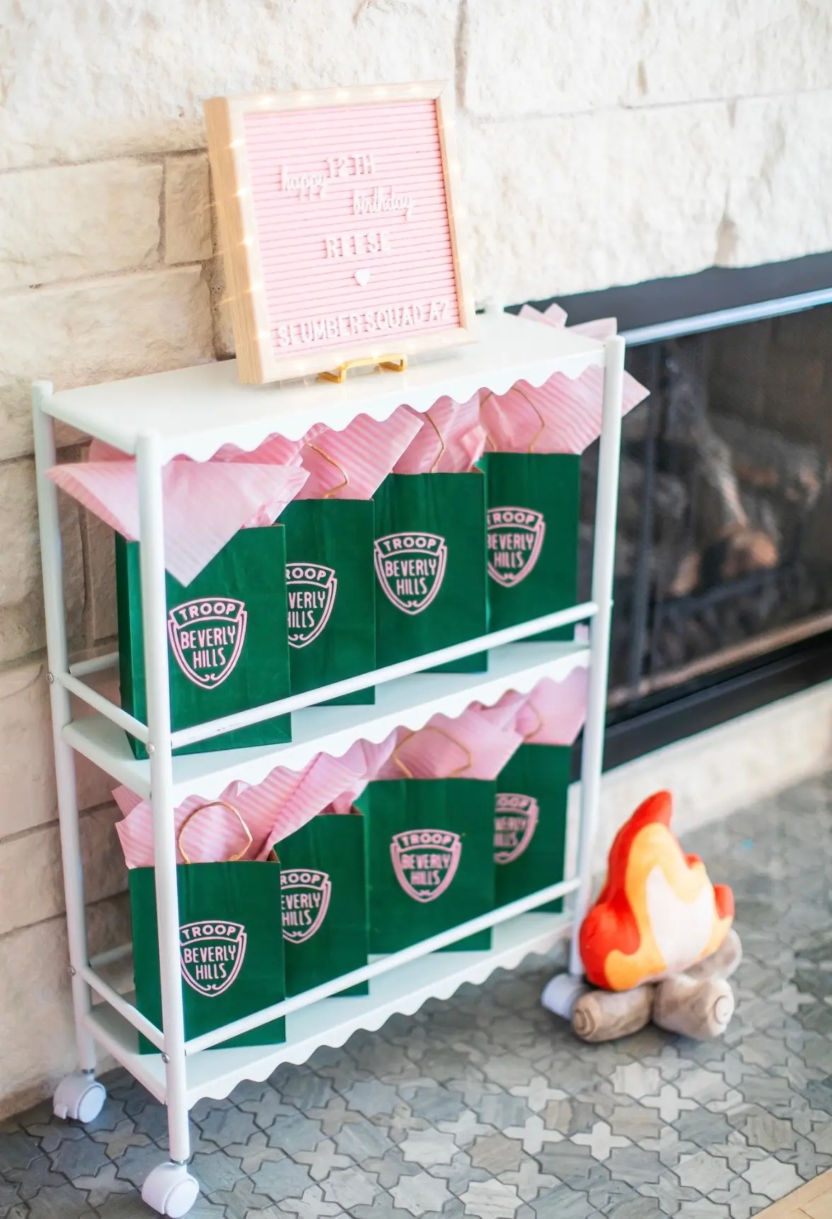 Party shelf with green favor bags by fireplace