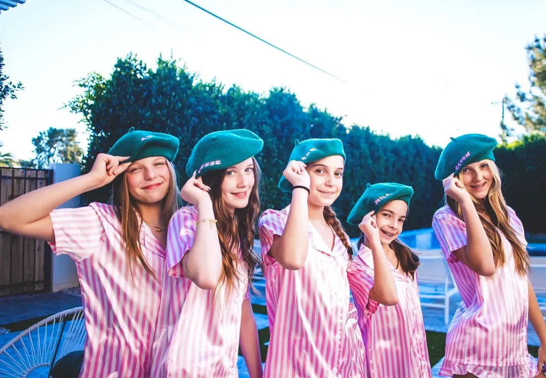 Five girls in pink pajamas wearing green berets