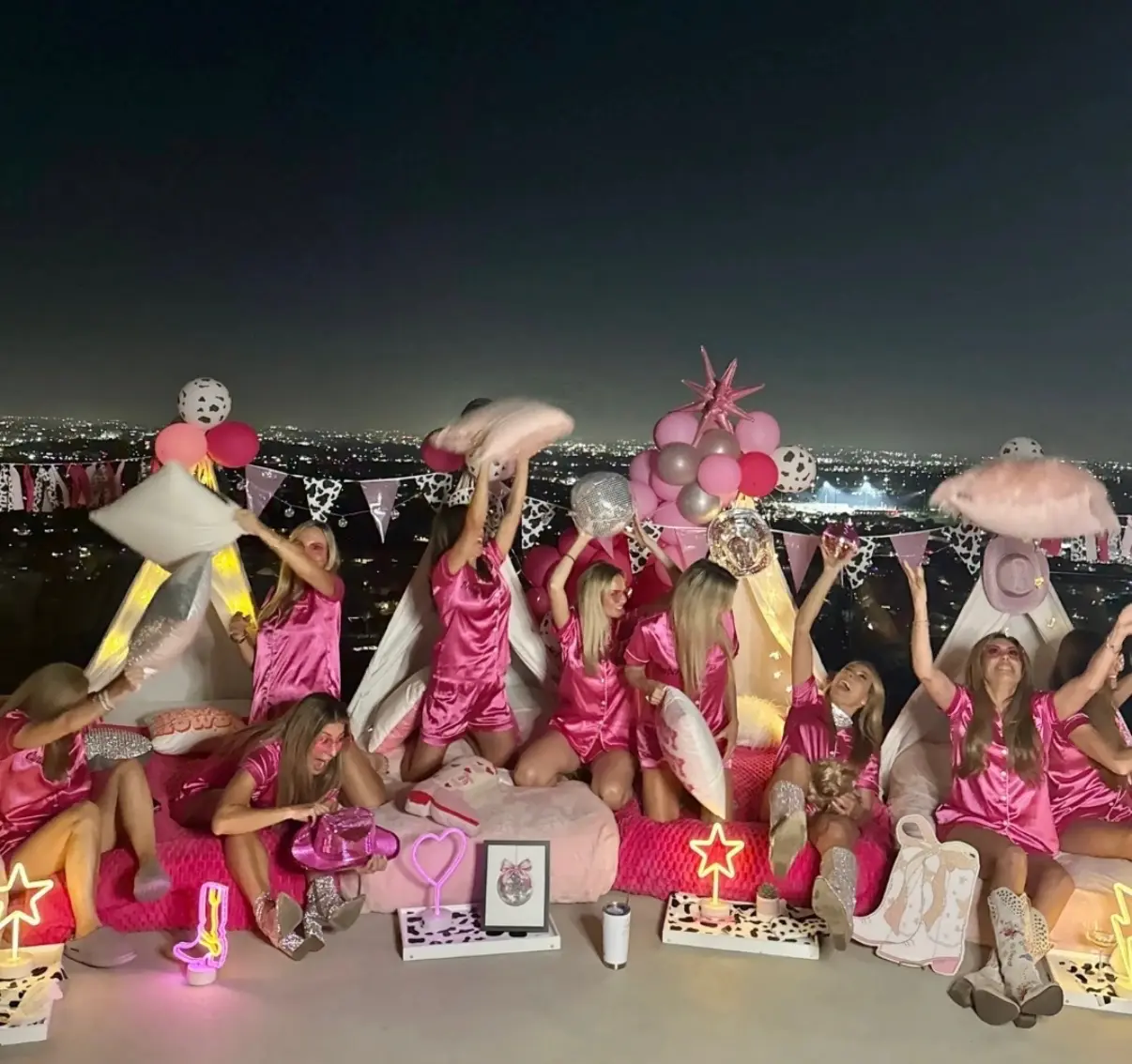 Women in pink pajamas pillow fight on rooftop