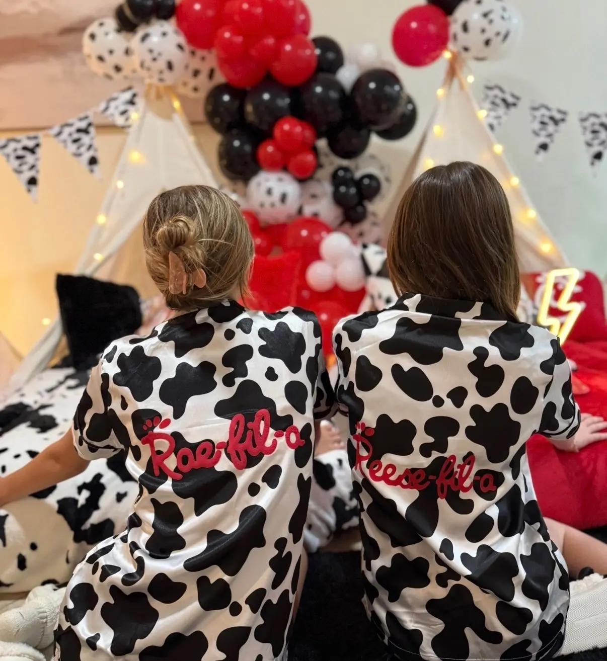 Two kids in cow-print shirts, balloon backdrop
