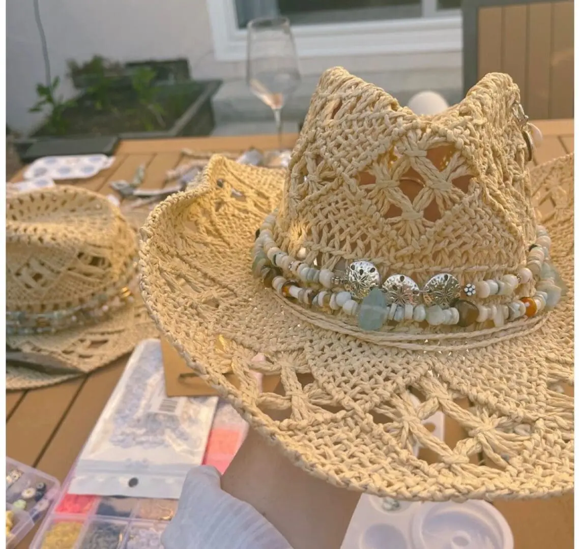 Two intricately crocheted straw hats placed on a table.