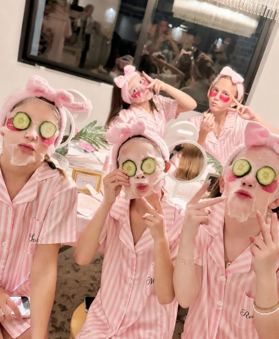 Group in pink pajamas wearing cucumber face masks