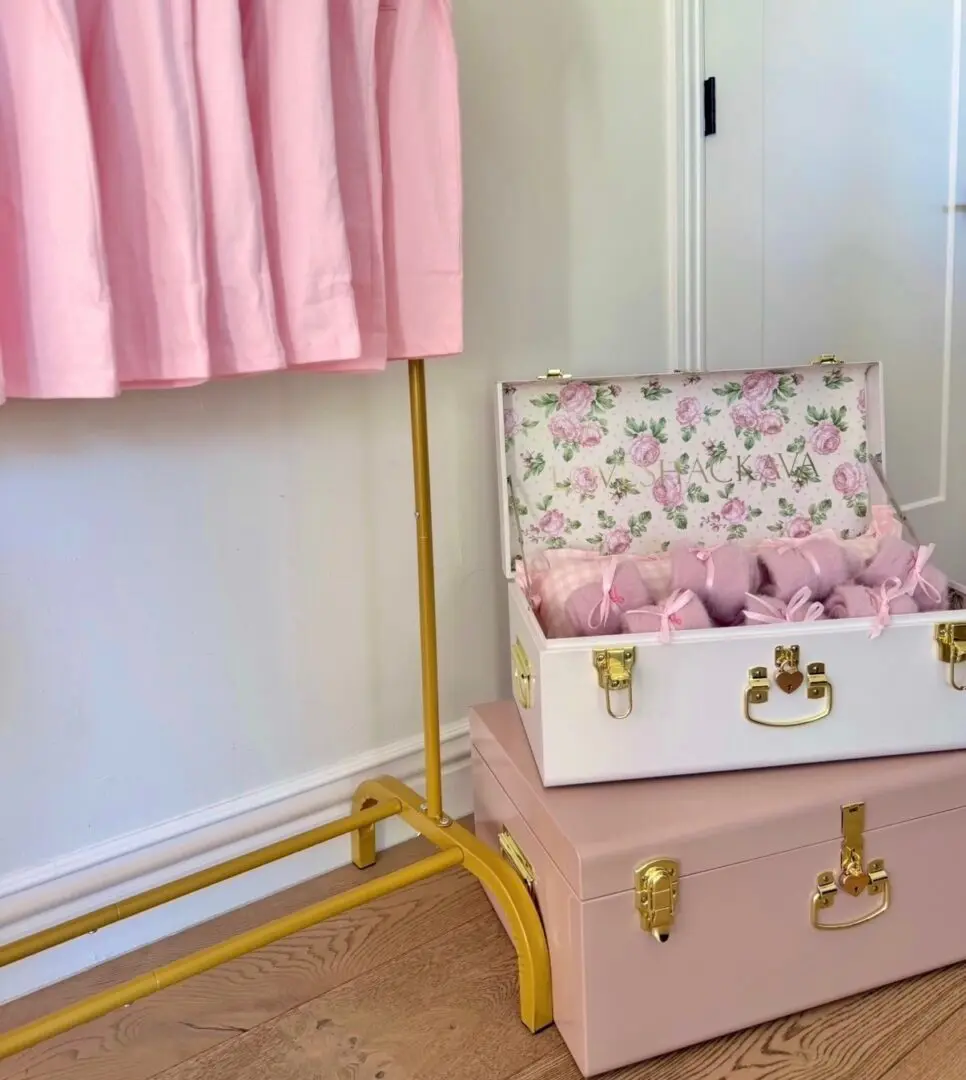 Open floral-lined pink suitcase beside pink dress