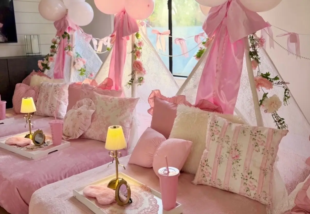 Pink teepee sleepover setup with floral pillows