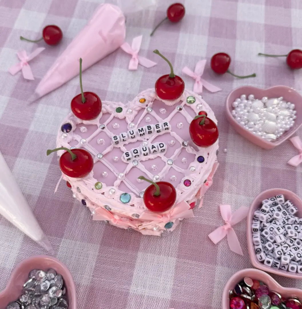 Pink heart-shaped cake with cherries and beads
