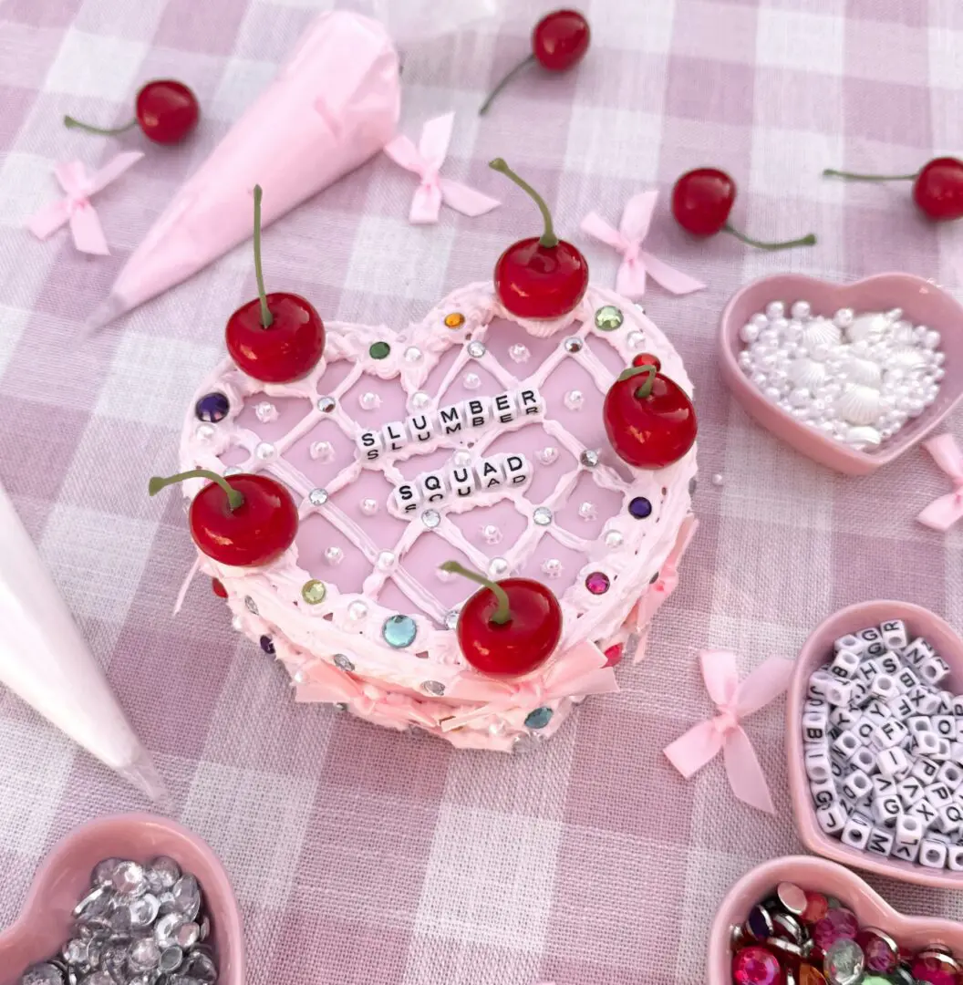 Heart-shaped pink cake with cherries and beads