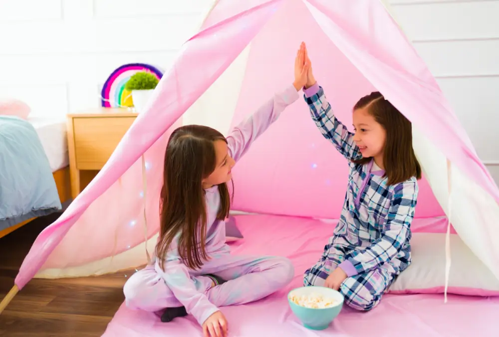 Two girls high-fiving in pink tent.