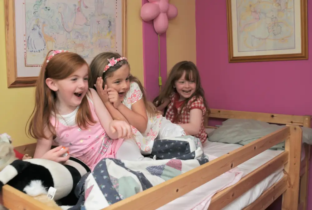 Three girls laughing on a bunk bed.